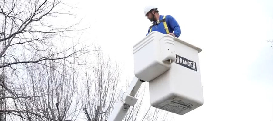 Telecommunications contractor in man lift on work truck